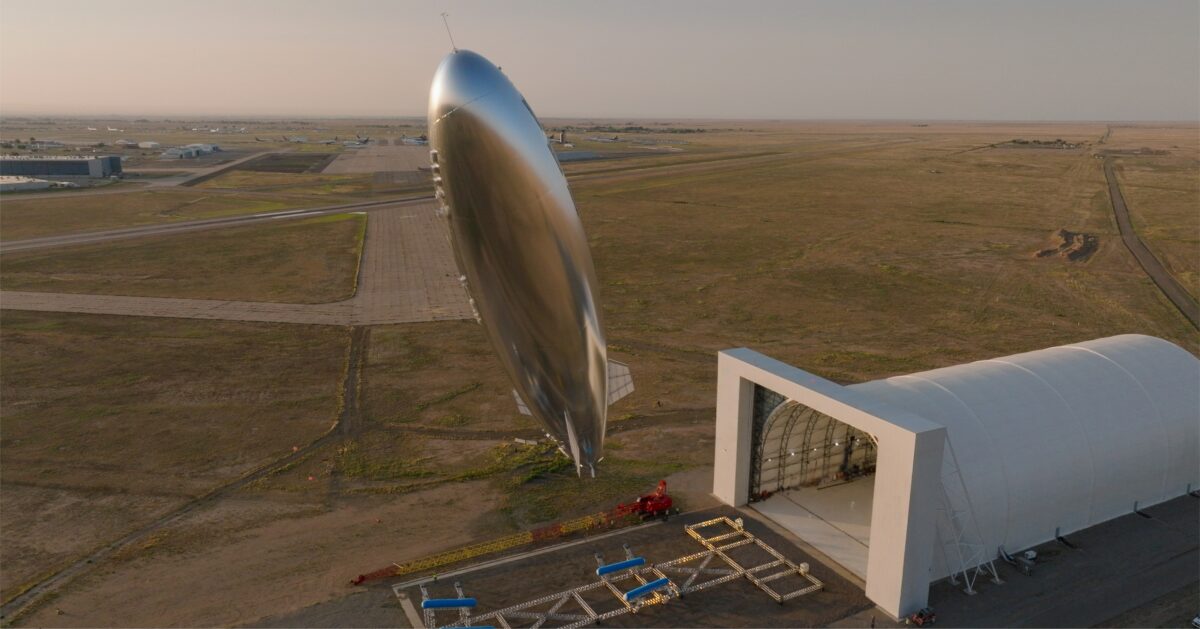 Aerial view of large airship stages beside airport hangars